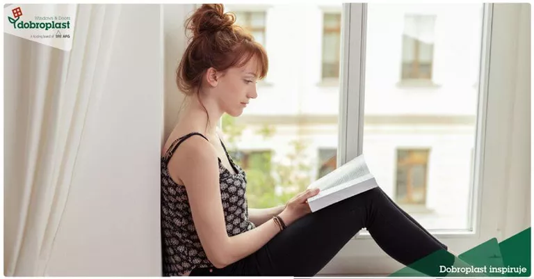 Kobieta czyta książkę, za oknem PCV Zielonka
